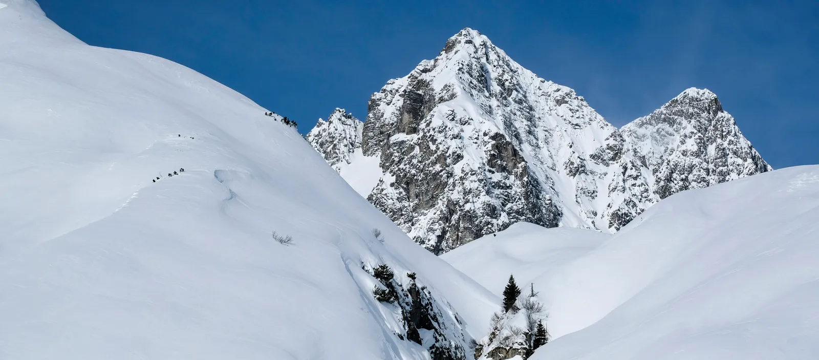 Sommet enneigé et pentes de ski dans les Alpes de l’Arlberg, par ciel bleu.